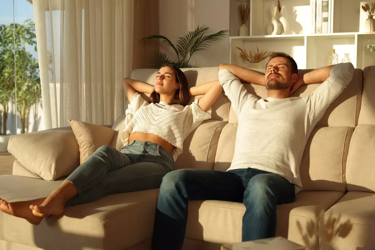 A couple basking in the sun in a living room.