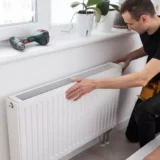 A worker installing a radiator.